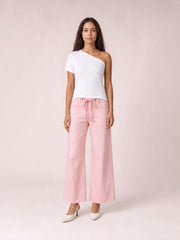 Model stands facing forward in pink wide-leg drawstring jeans with a tied waist, front pockets, seam details, and a cropped full-length silhouette.
