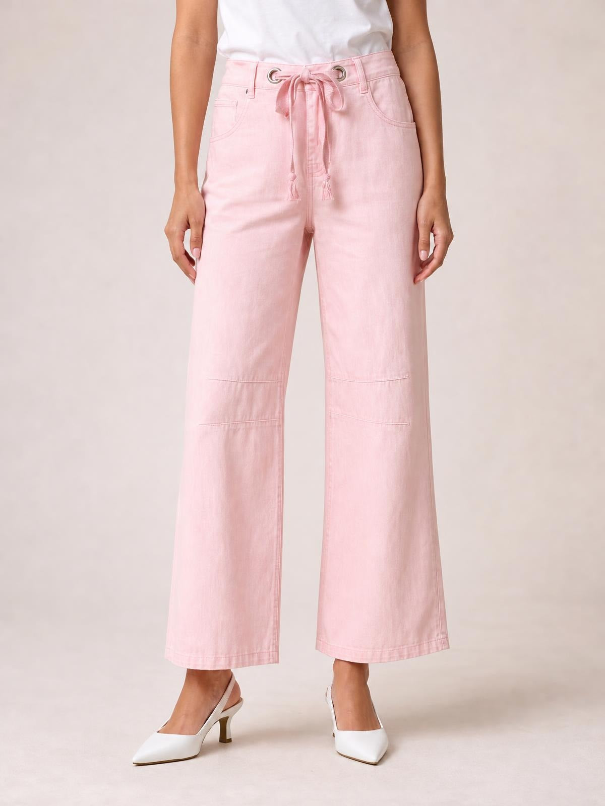 Model wearing pink wide-leg drawstring jeans with a tied waist, front pockets, belt loops, and straight stitched panel details.