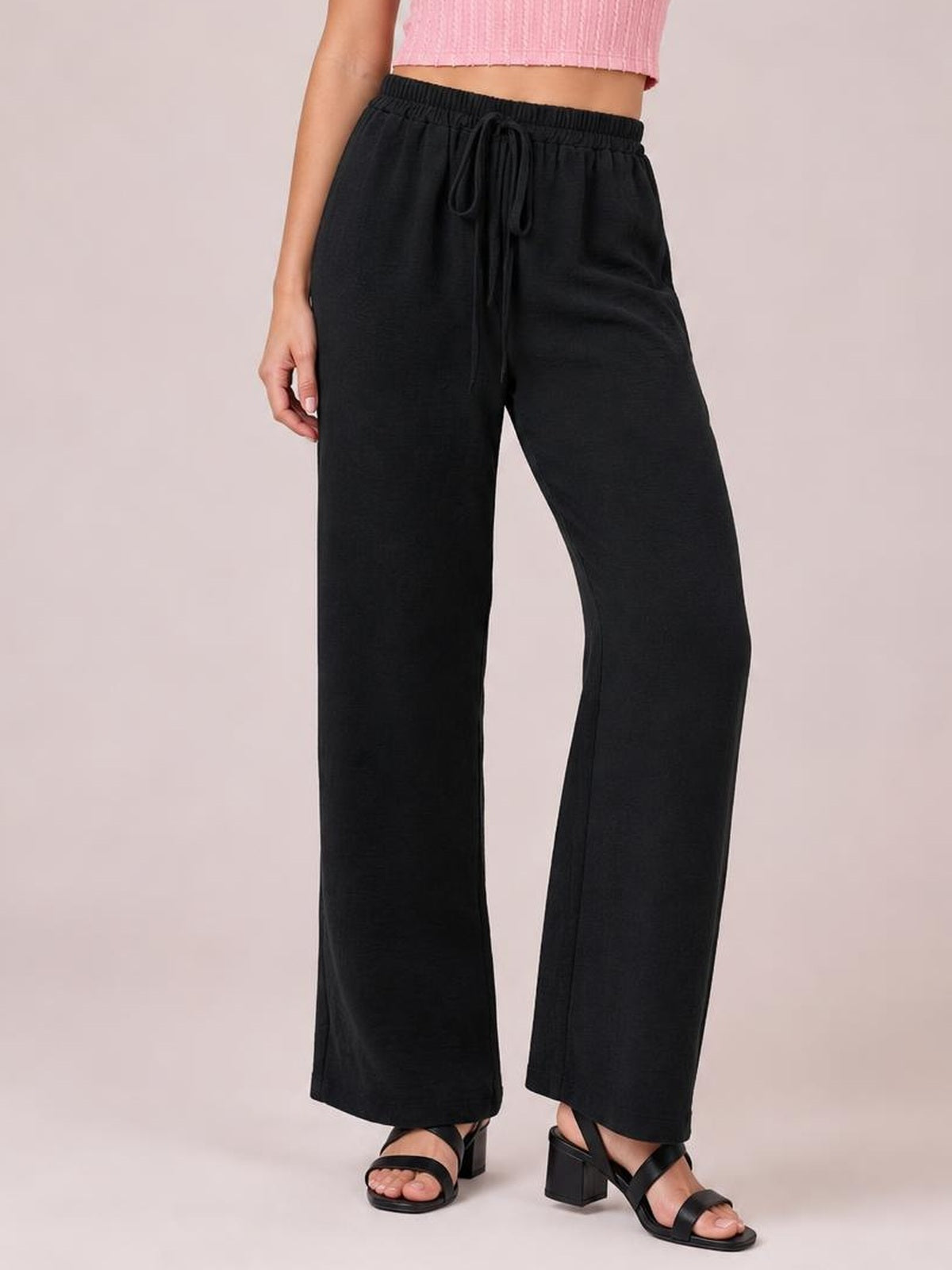 Model wearing black wide leg drawstring pants with an elasticized waist, relaxed flowy silhouette, and straight full-length legs.