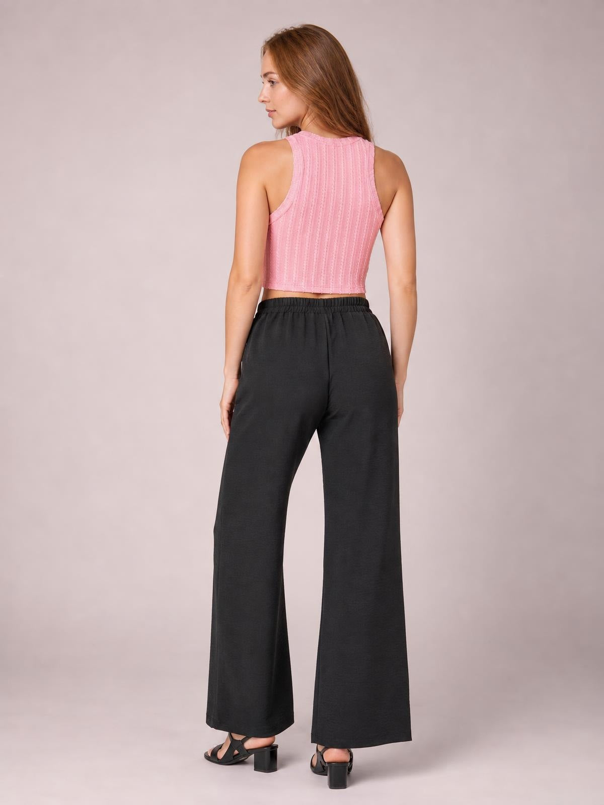 Model shown from the back wearing black wide leg drawstring pants with an elasticized waist and relaxed, flowing silhouette.