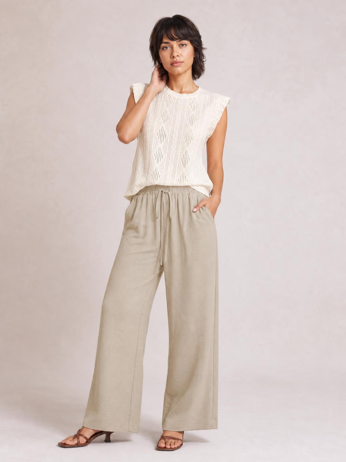 Model poses in beige wide leg drawstring pants with a relaxed flowy silhouette, elastic waistband, long straight legs, and side pockets.