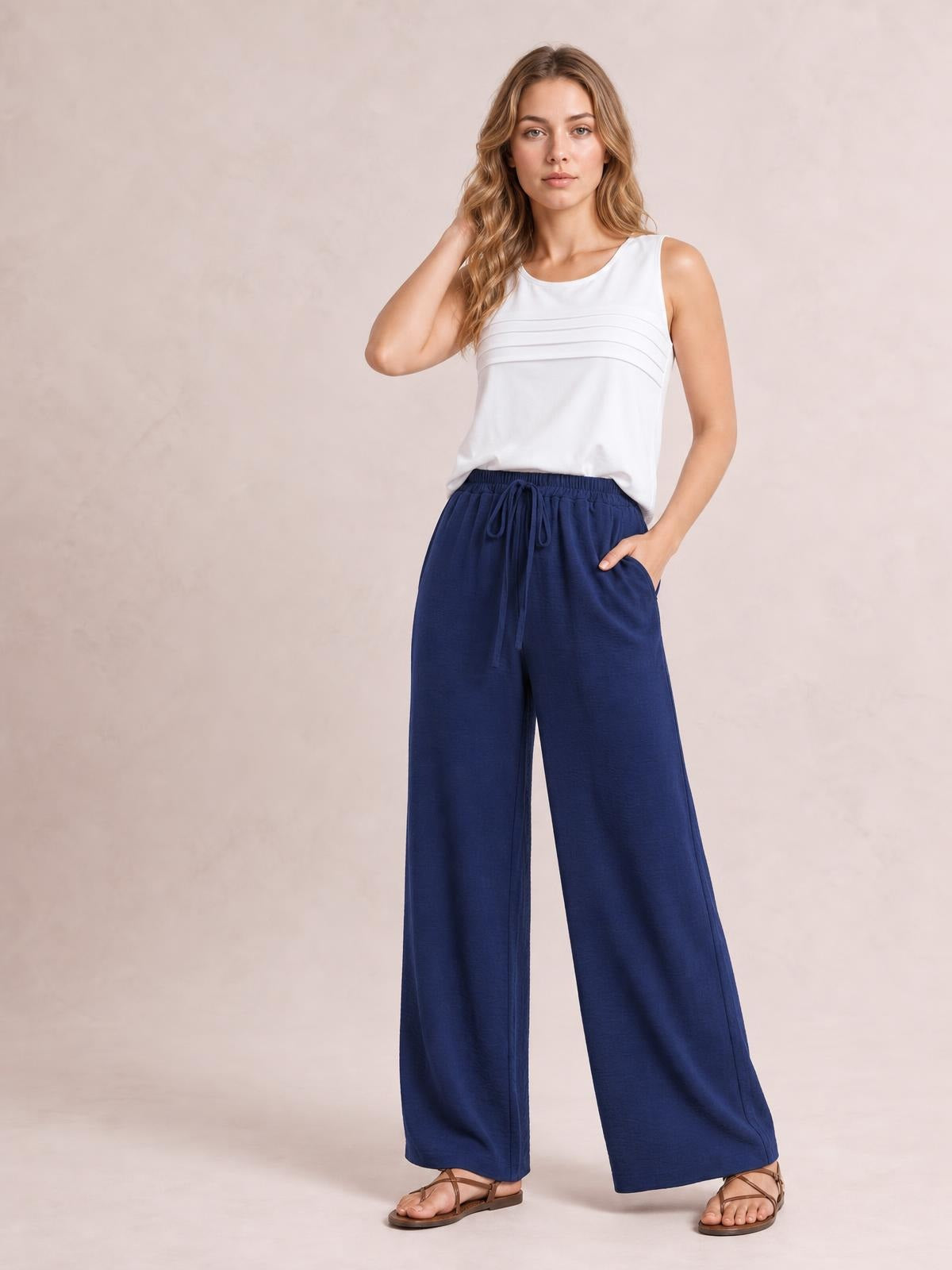 Model wearing navy wide-leg drawstring pants with a relaxed flowy silhouette, elasticized waist, visible tie, and side pockets.