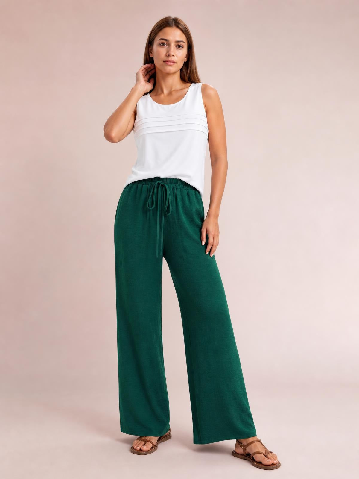 Model standing in dark green wide-leg drawstring pants with a relaxed, flowy silhouette, elastic waist, and long straight legs.