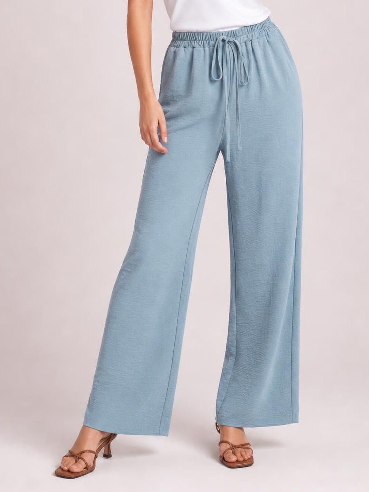 Model wearing light blue wide leg drawstring pants with a relaxed, flowy silhouette, elastic waistband, and front tie detail.