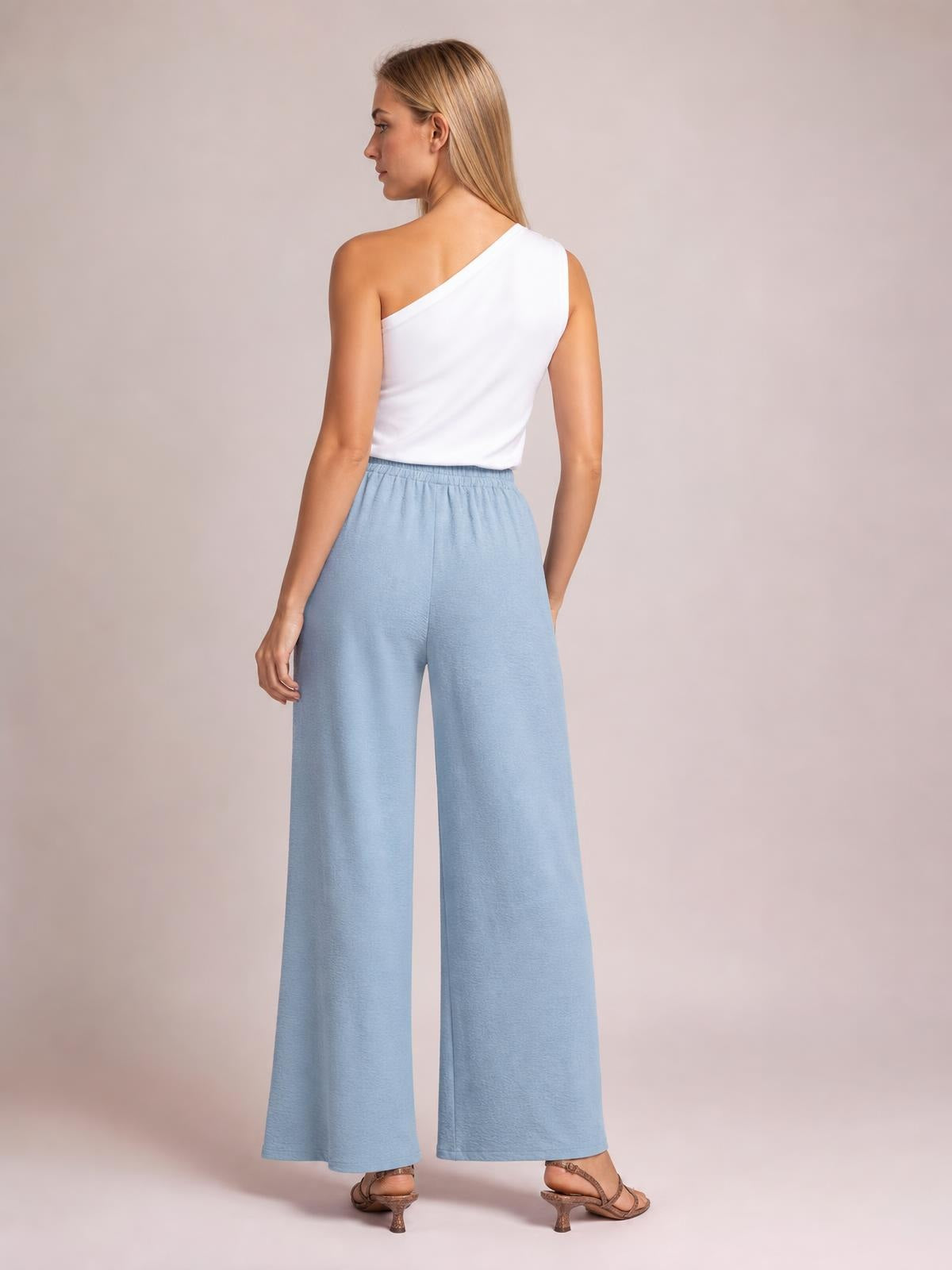 Model shown from behind in light blue wide leg drawstring pants with an elasticized waist and flowy, full-length silhouette.