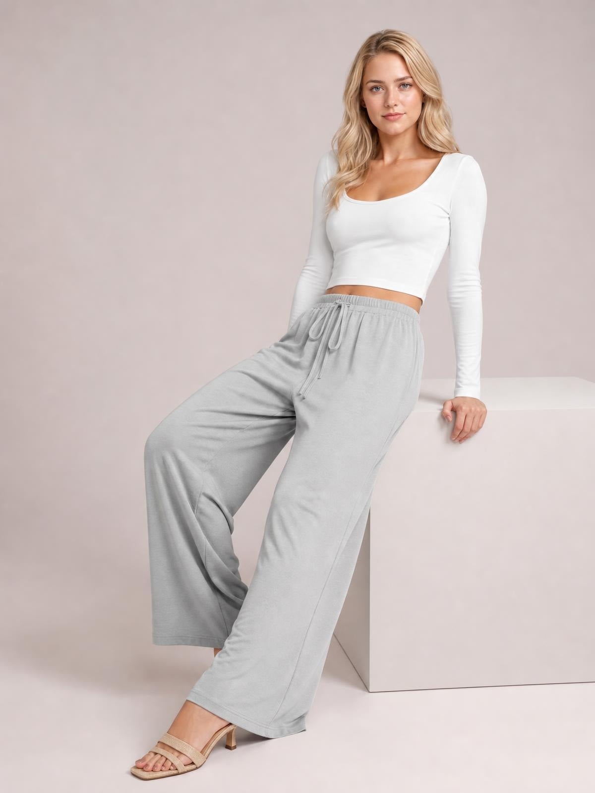 Model poses in light gray wide-leg drawstring pants with a relaxed flowy silhouette, elasticized waist, and adjustable front tie.