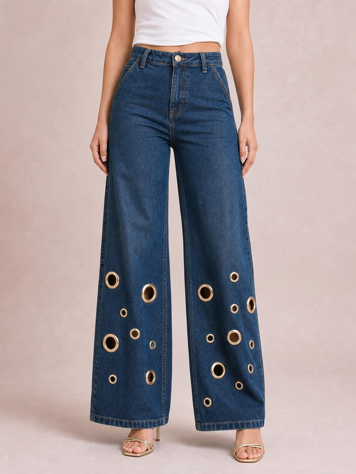 Model stands with hands at her sides wearing dark blue wide-leg jeans with a high waist, classic five-pocket construction, and gold eyelet details along the lower legs.