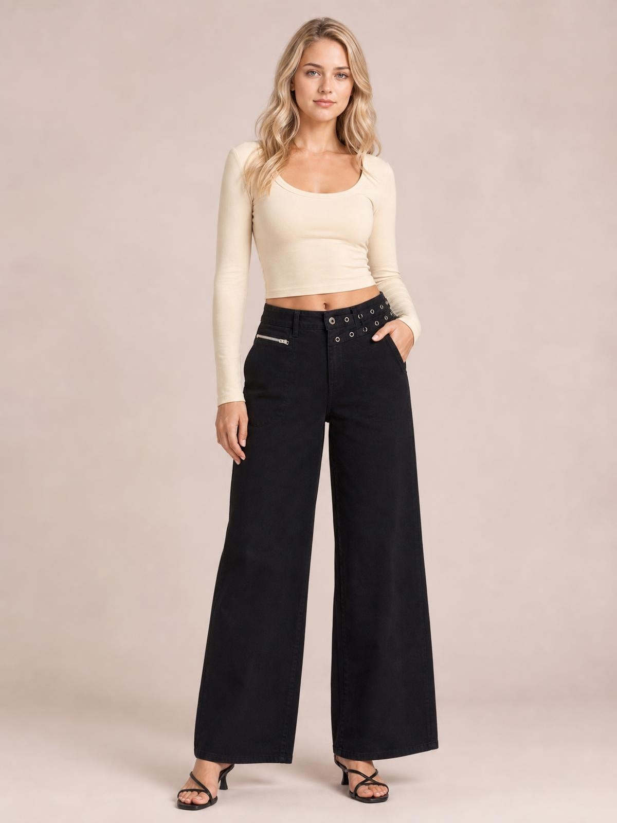 Model stands with one hand in the pocket, wearing black wide leg jeans with a high-rise waist, front pockets, belt loops, and a full-length silhouette.
