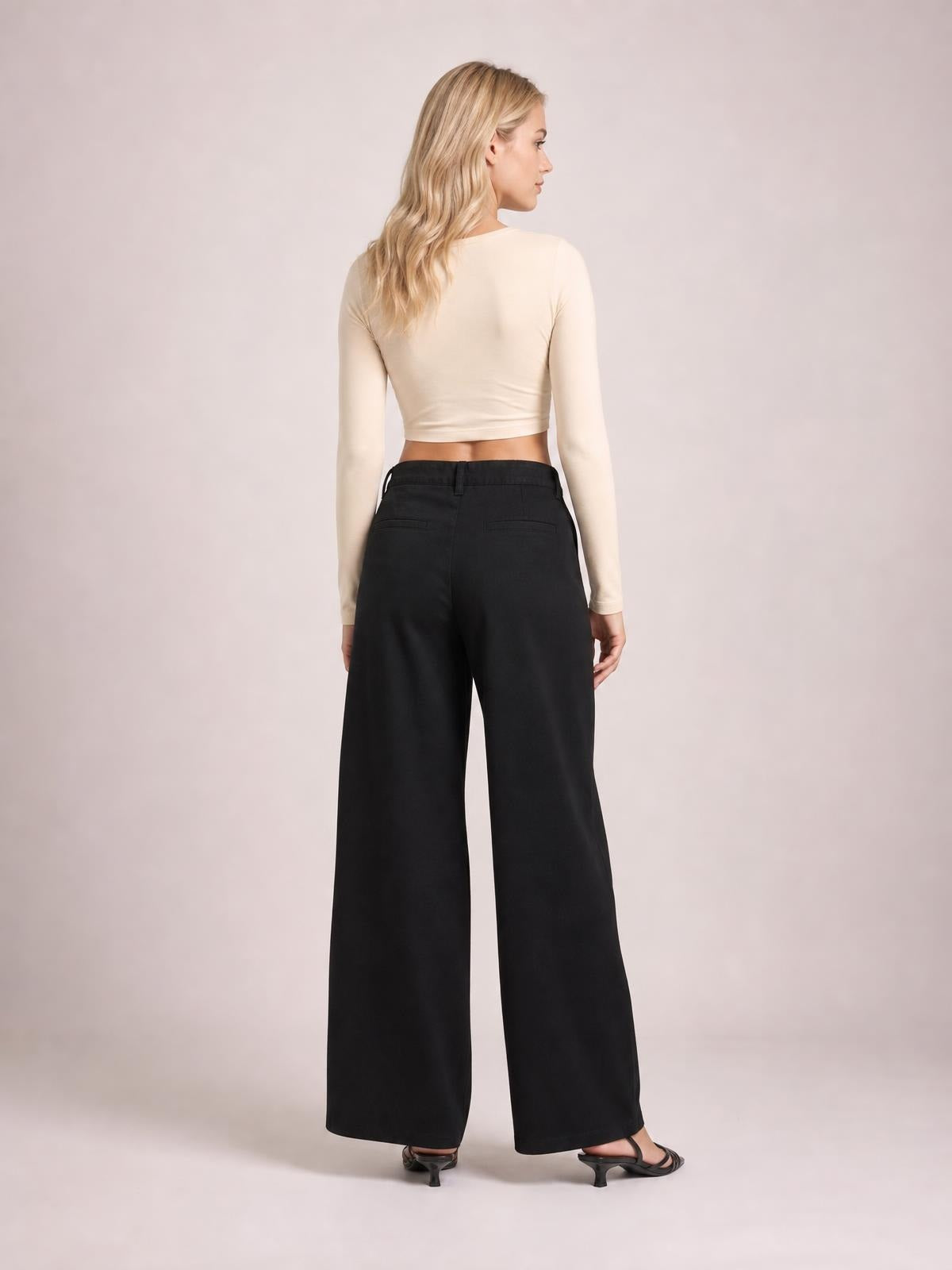 Model shown from behind wearing black wide leg jeans with back pockets, a structured waistband, and a full-length relaxed silhouette.