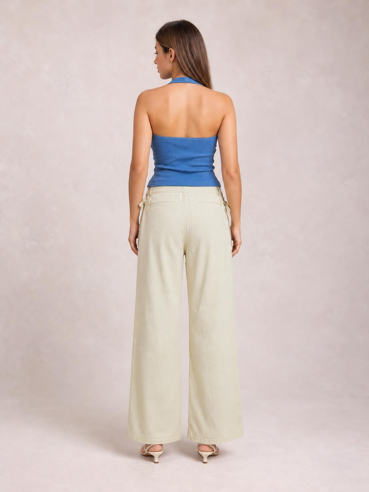 Back view of a model standing in cream wide-leg jeans with visible side and back pockets, a structured waistband, and full-length relaxed legs.