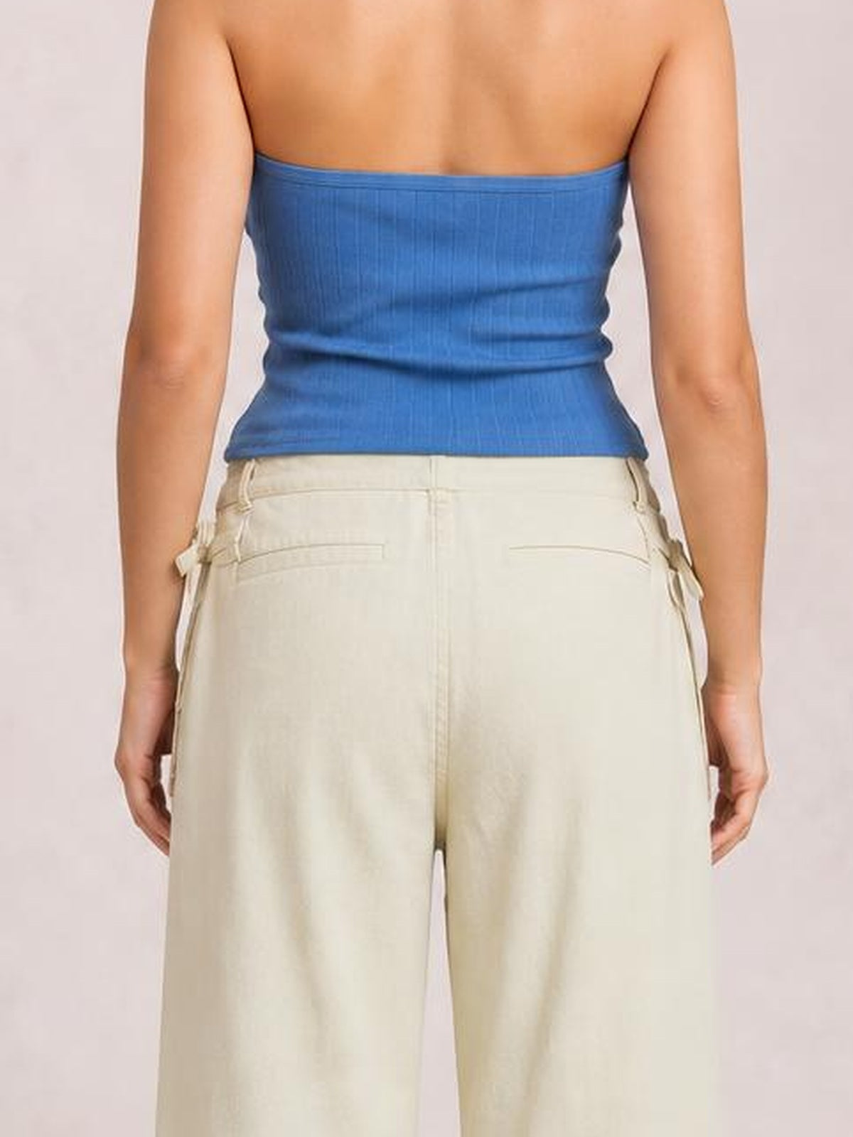 Model shown from behind wears cream wide-leg jeans with visible back pockets, a structured waistband, straight seams, and a relaxed silhouette.