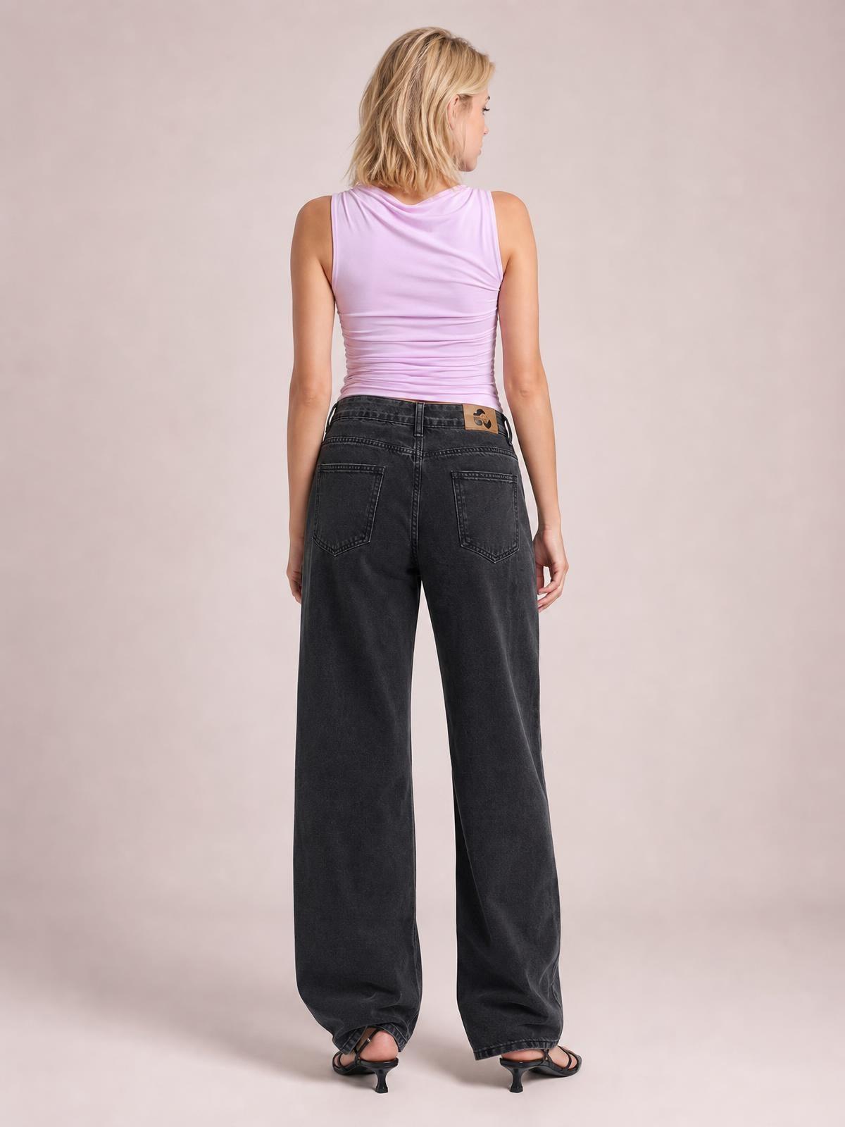 A model stands in dark gray wide leg jeans with a buttoned waist, roomy full-length silhouette, and two visible back pockets.
