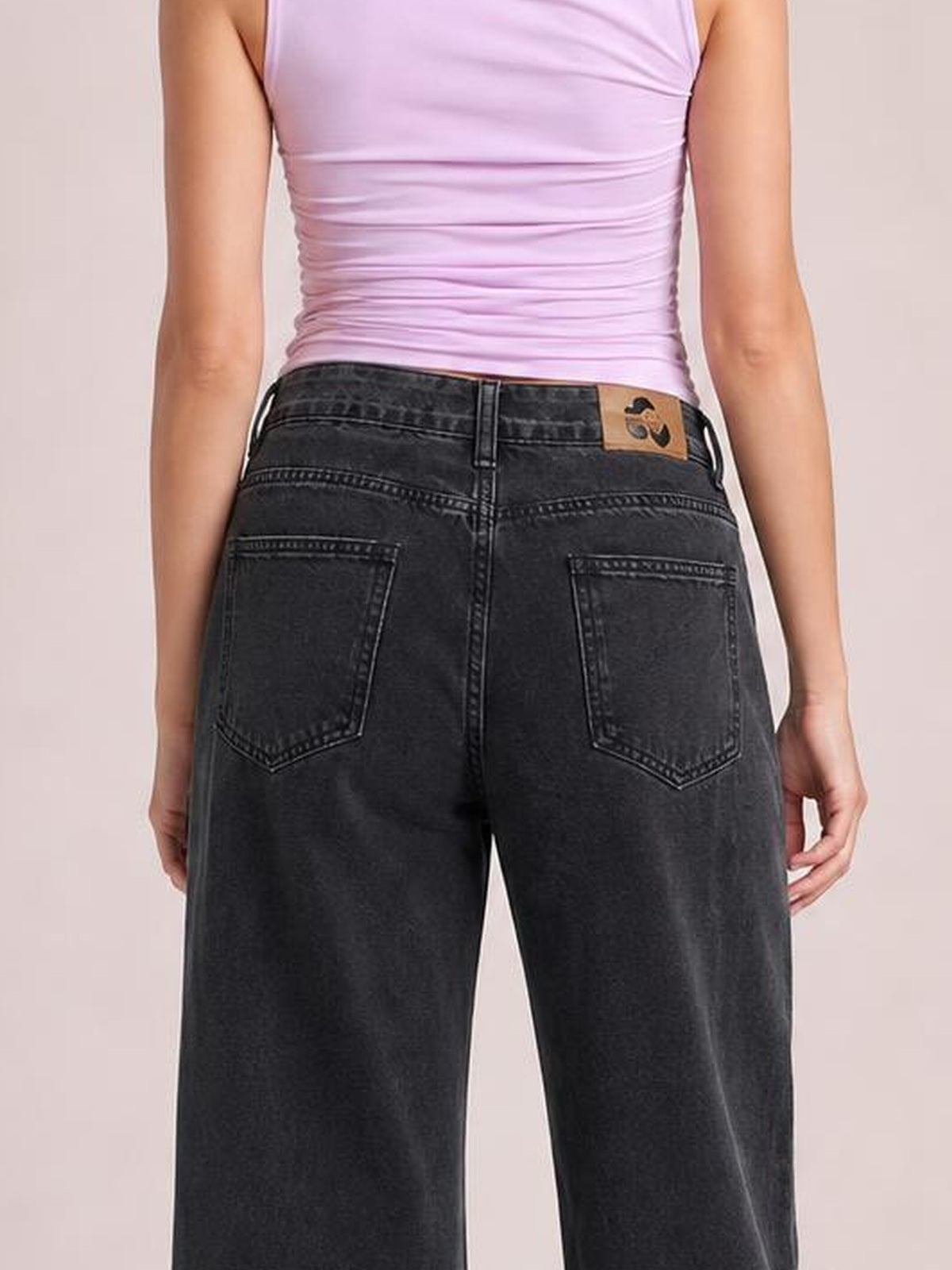 Model shown from behind wearing black wide-leg jeans with a relaxed silhouette, belt loops, buttoned waistband, and two stitched back pockets.