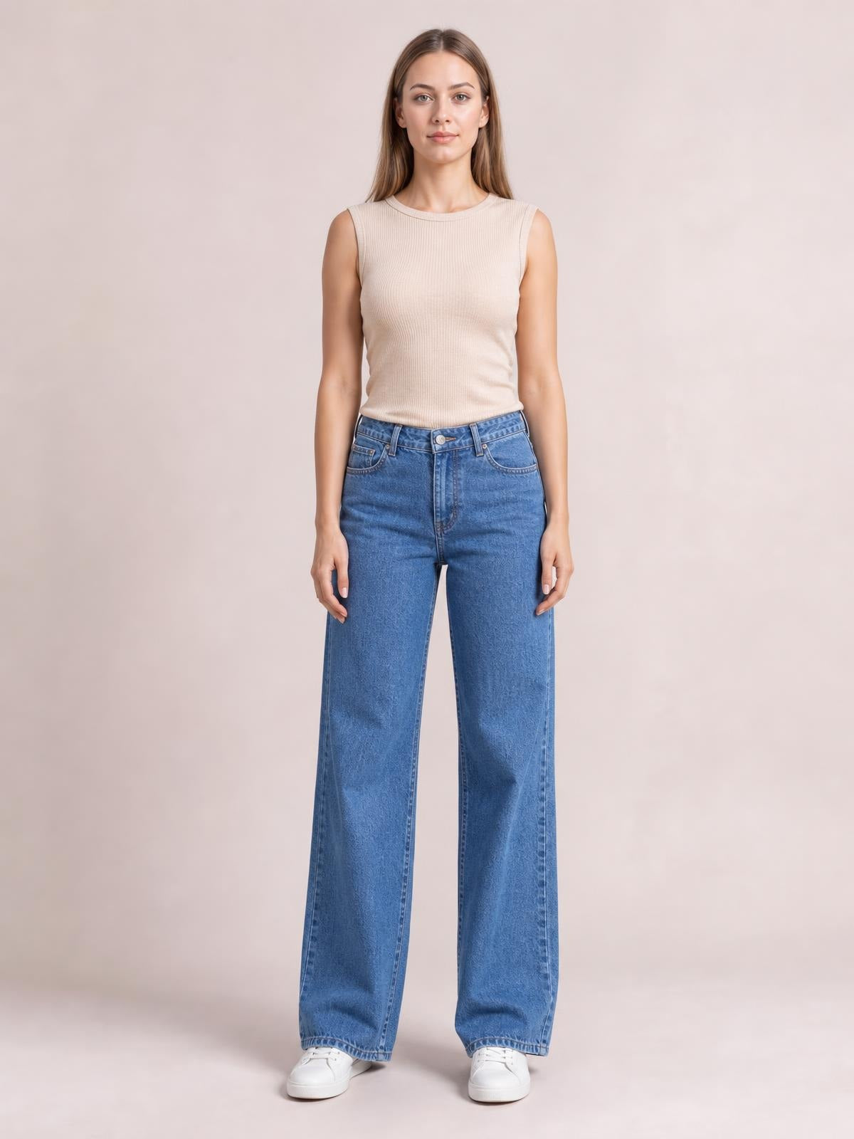 Model stands facing forward in blue wide leg jeans with front pockets, belt loops, button closure, and a relaxed full-length silhouette.