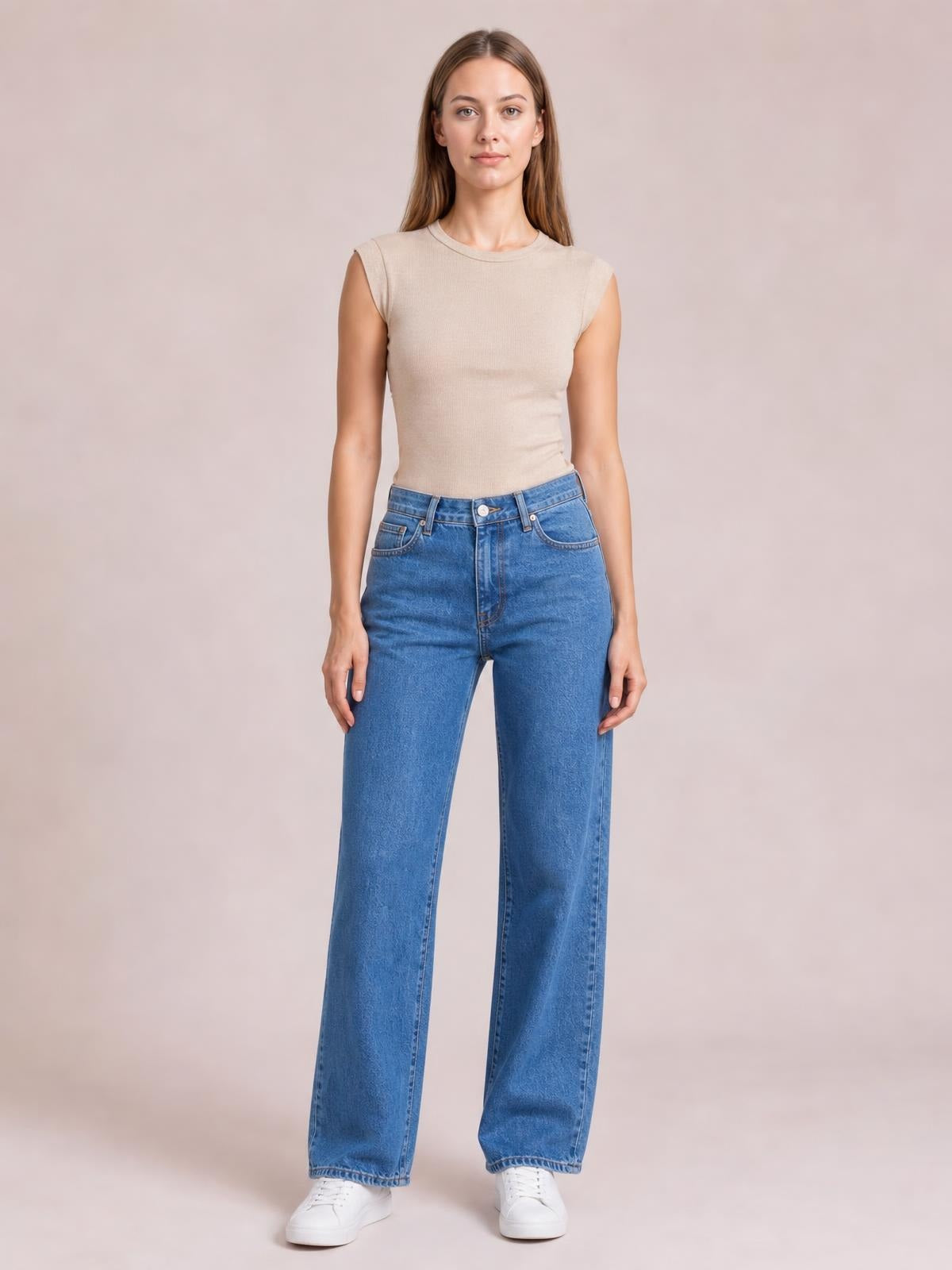 Model standing in blue wide leg jeans with front pockets, a button fly, belt loops, high waist, and relaxed straight silhouette.