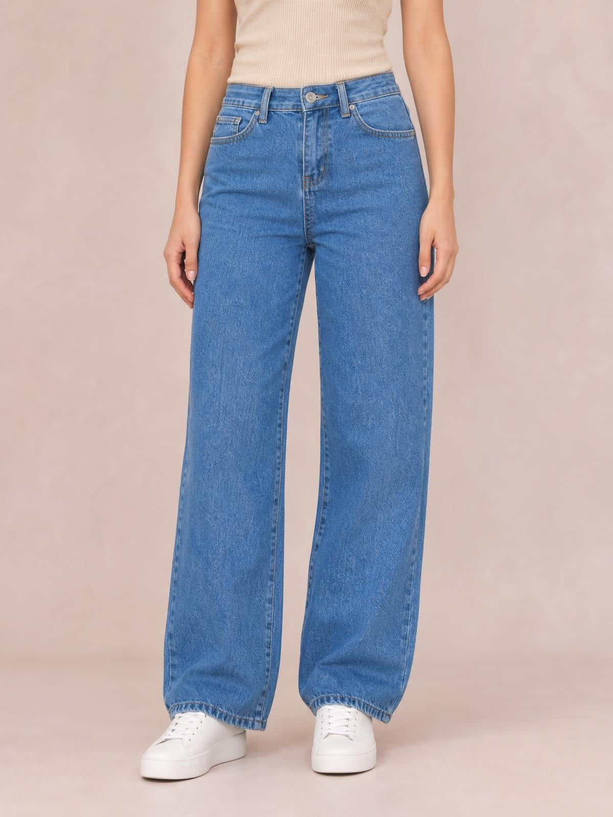 Model wearing blue wide-leg jeans with front pockets, belt loops, a button closure, straight construction, and full-length hems.
