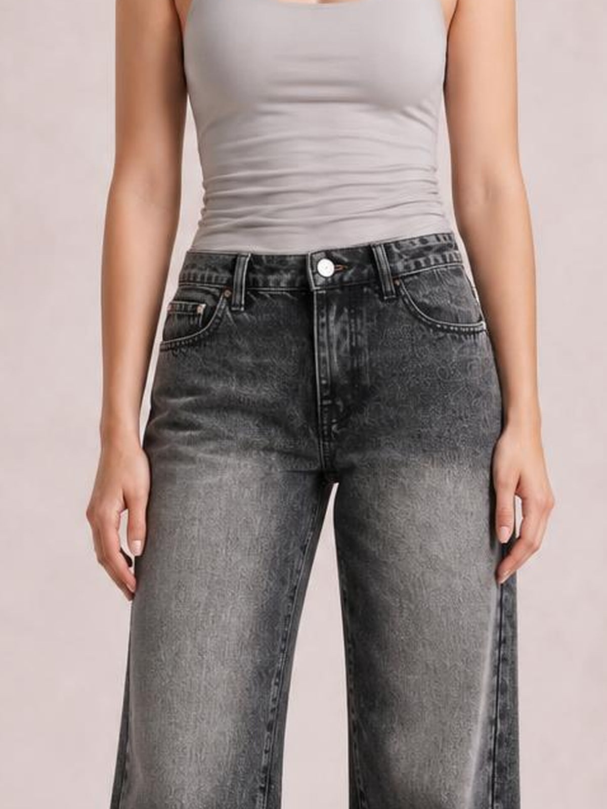 Model wears dark gray wide-leg jeans with a button closure, belt loops, front pockets, and contrast fading, standing with hands at her sides.