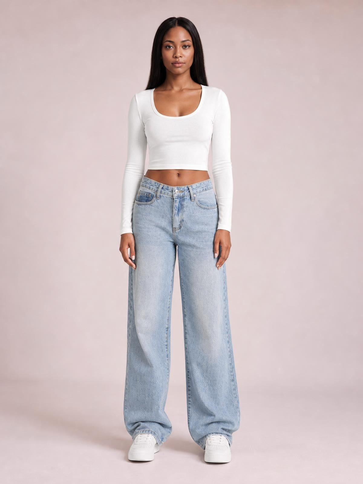 Model standing in light-wash wide leg jeans with front pockets, belt loops, button closure, and a relaxed full-length silhouette.