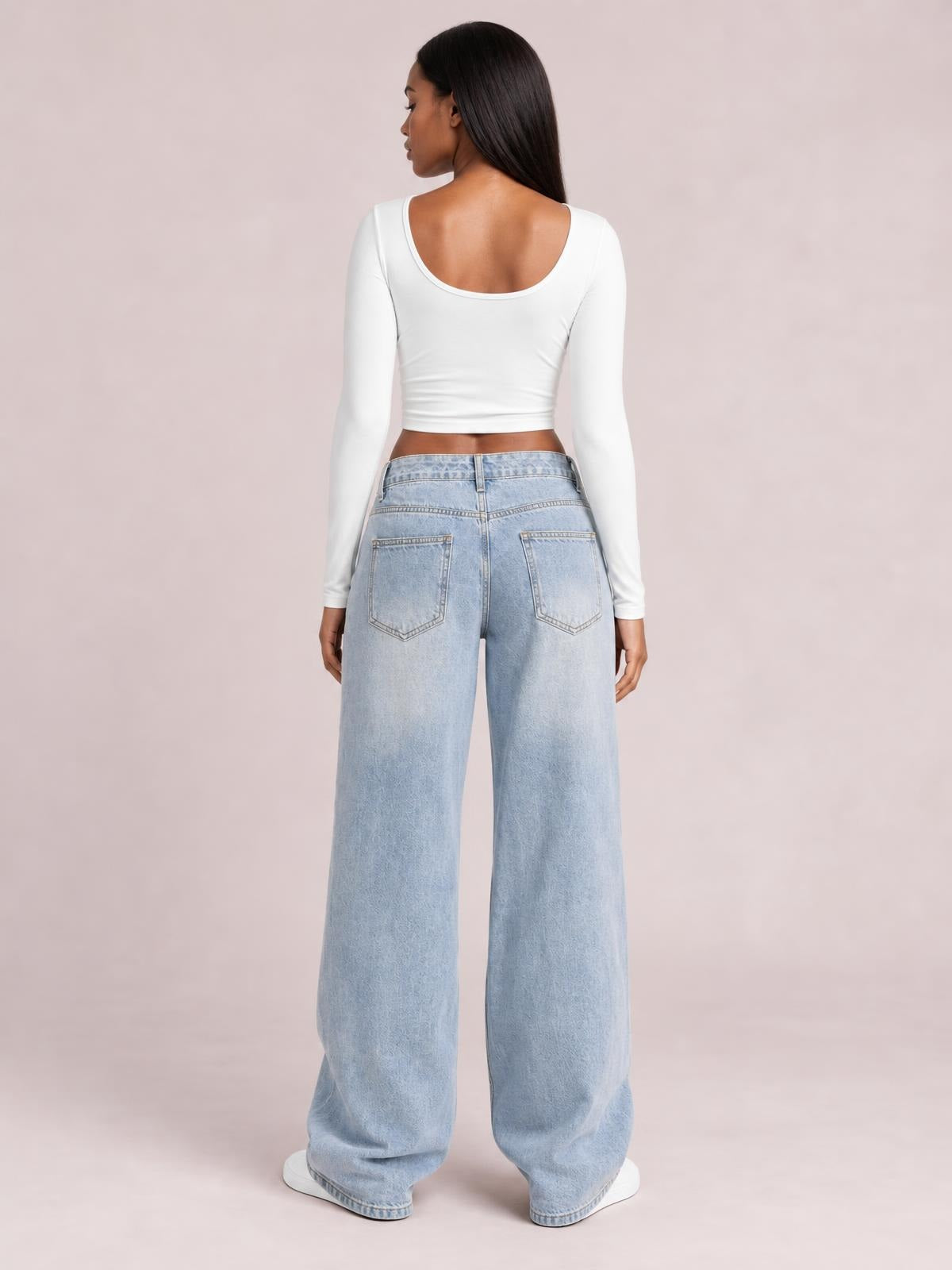 Model shown from the back in light-wash wide leg jeans with a buttoned waistband, belt loops, and two stitched back pockets.