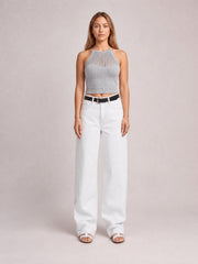Model standing in white wide-leg jeans with front pockets, belt loops, and a buttoned high-rise waistband, creating a relaxed full-length silhouette.