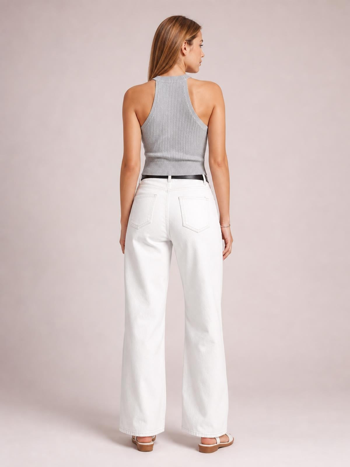 Model shown from behind in white wide leg jeans with a high-rise waistband, belt loops, button closure, and two back pockets, standing in a relaxed pose.