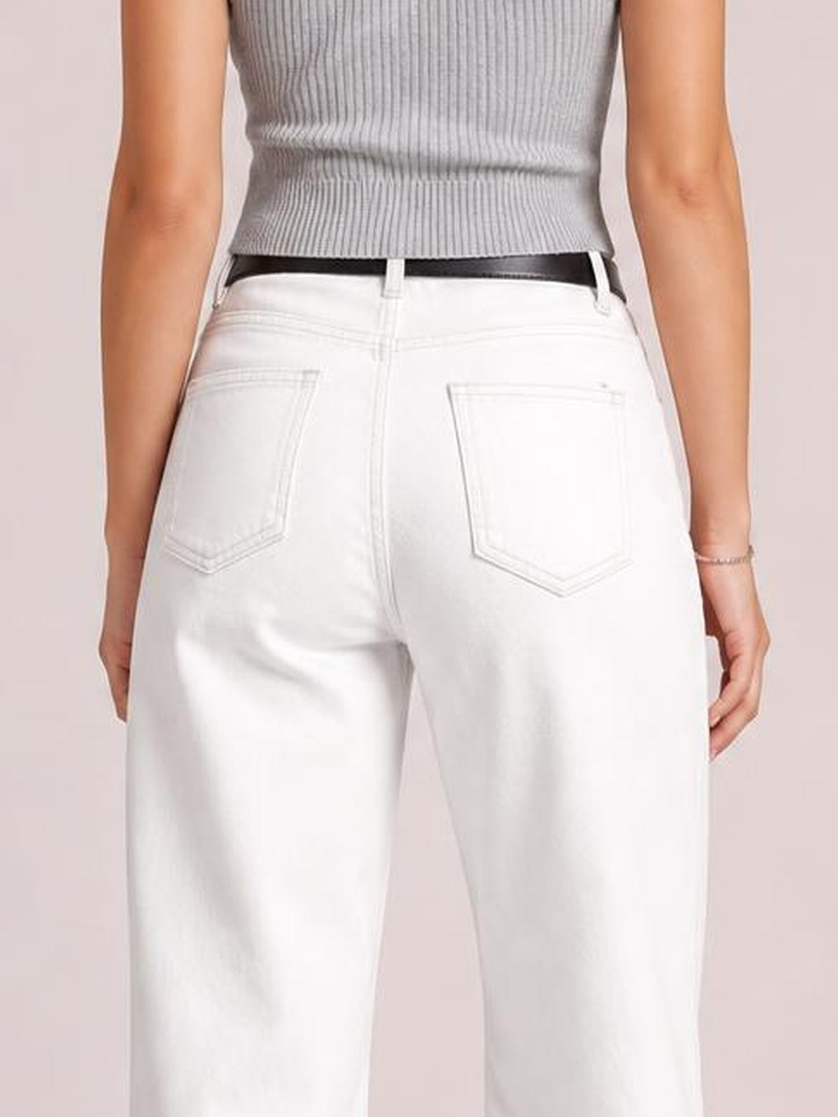 Model shown from the back wearing white wide leg jeans with a high waist, belt loops, buttoned closure, and stitched back pockets.