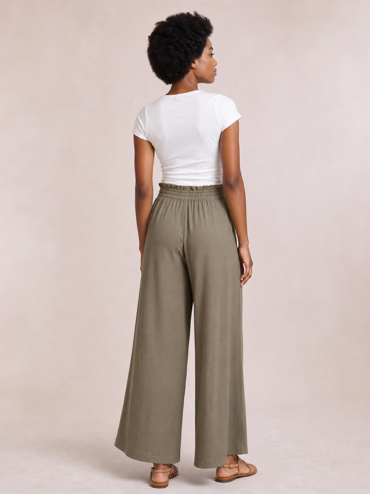 Model shown from behind in olive wide leg pants with side pockets, an elasticized waistband, and a fluid full-length silhouette.