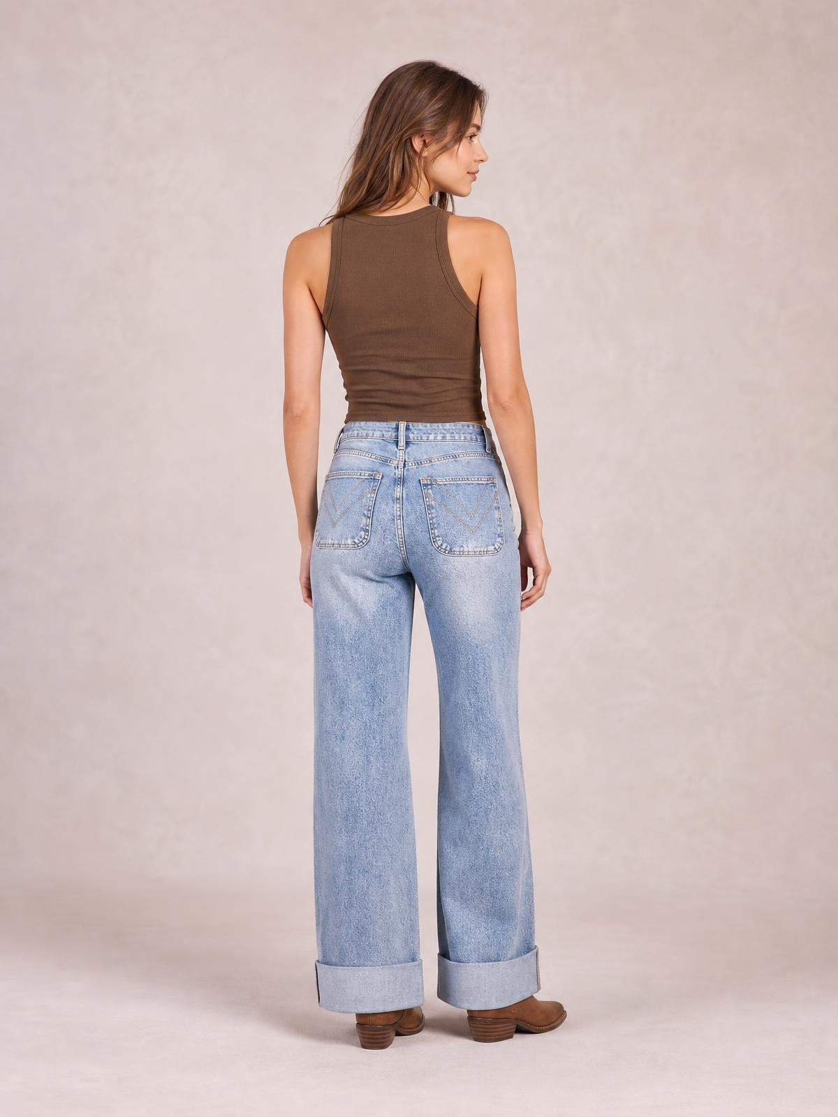 Model shown from behind in light-wash wide-leg jeans with a high waist, large back pockets, belt loops, and wide cuffed hems.