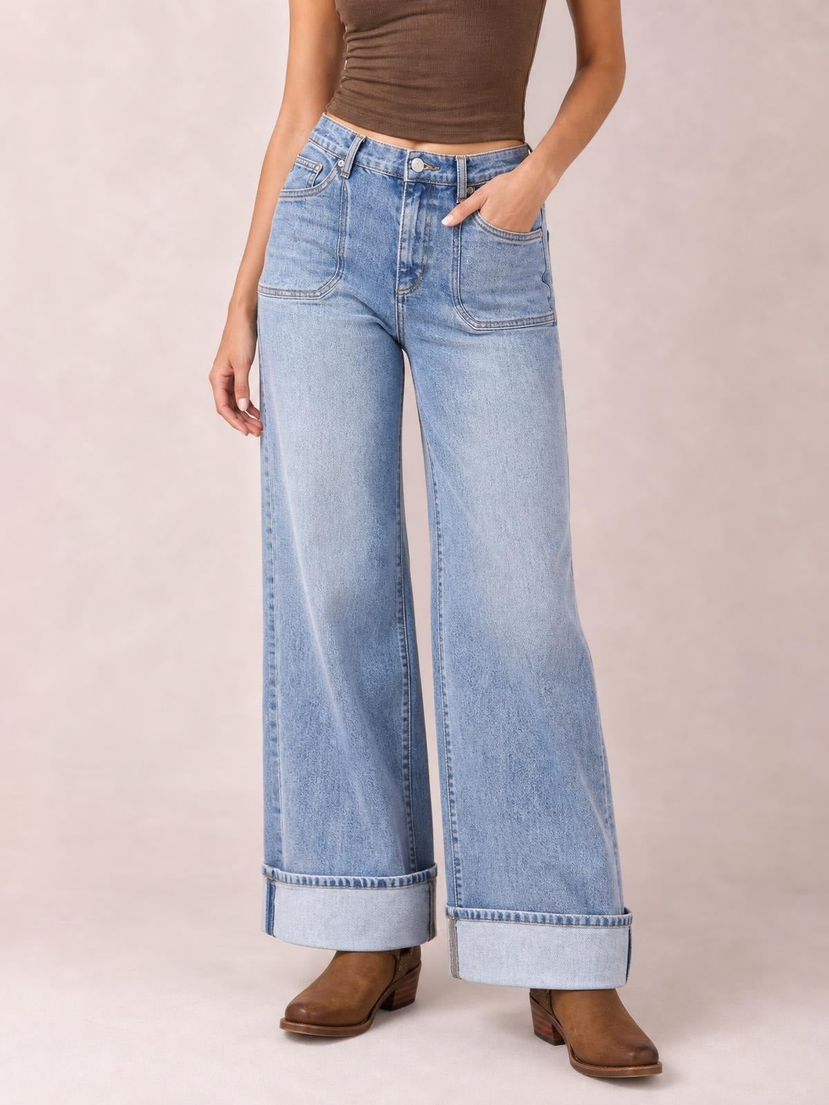 Model wearing light-wash wide-leg jeans with a high waist, oversized front pockets, belt loops, button fly, and wide cuffed hems.