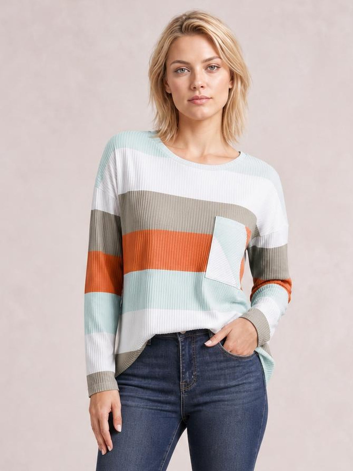 Model wearing a relaxed wide stripe top with long sleeves, crew neckline, multicolor horizontal bands, ribbed texture, and a front patch pocket.