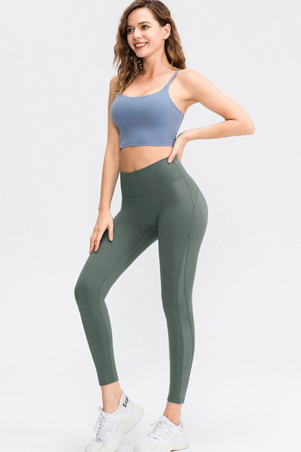 Model poses in dark green wide-waistband slim-fit long sports leggings, showing a solid color and body-hugging silhouette.