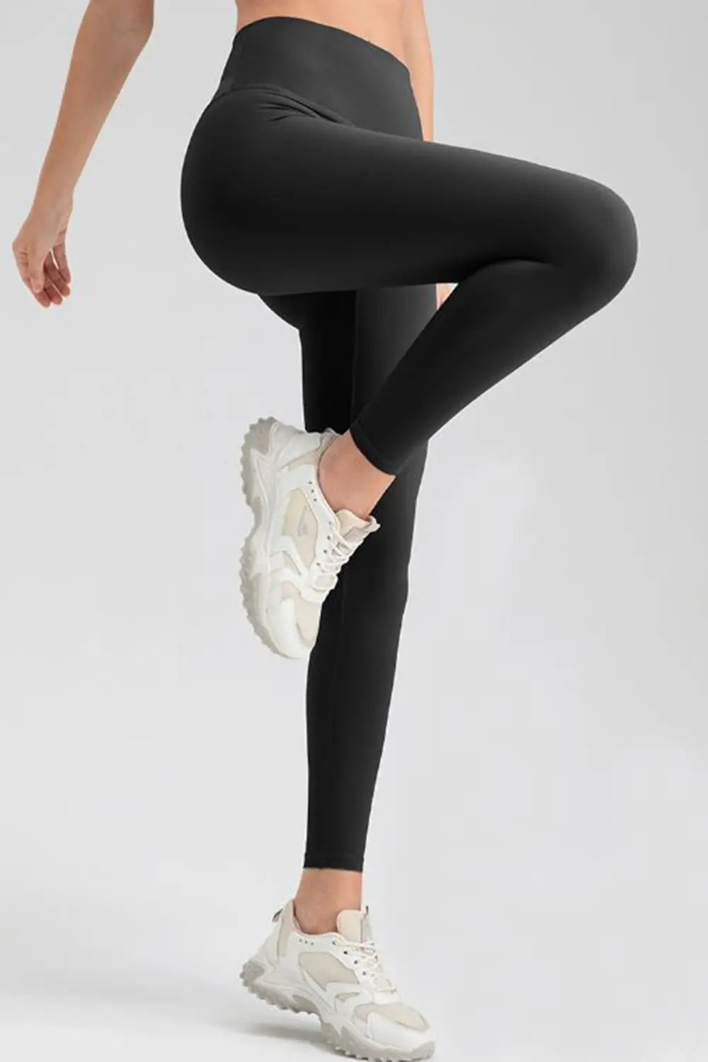 Model crouching in black wide-waistband sport leggings, showcasing a sleek full-length stretch silhouette with a smooth, basic construction.