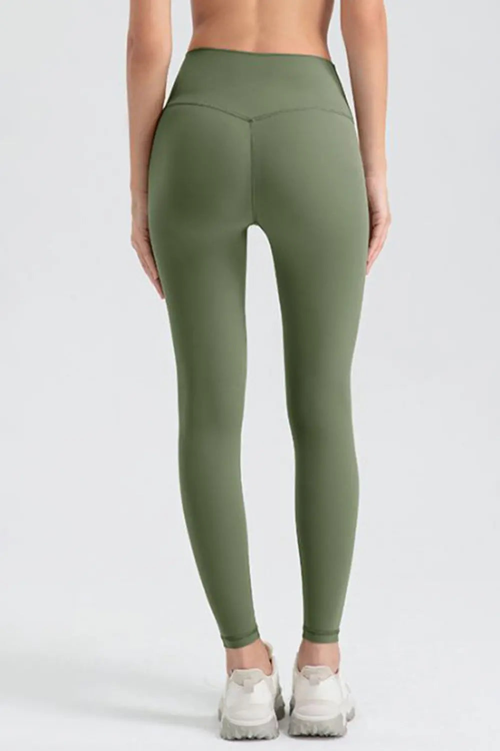 Model shown from behind wearing olive green wide waistband sport leggings with a high-rise fit, smooth construction, fitted legs, and ankle-length silhouette.