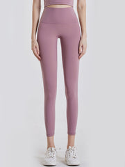 Model stands with hands at her sides wearing mauve wide waistband sports leggings in an opaque, stretchy, close-fitting ankle-length silhouette.