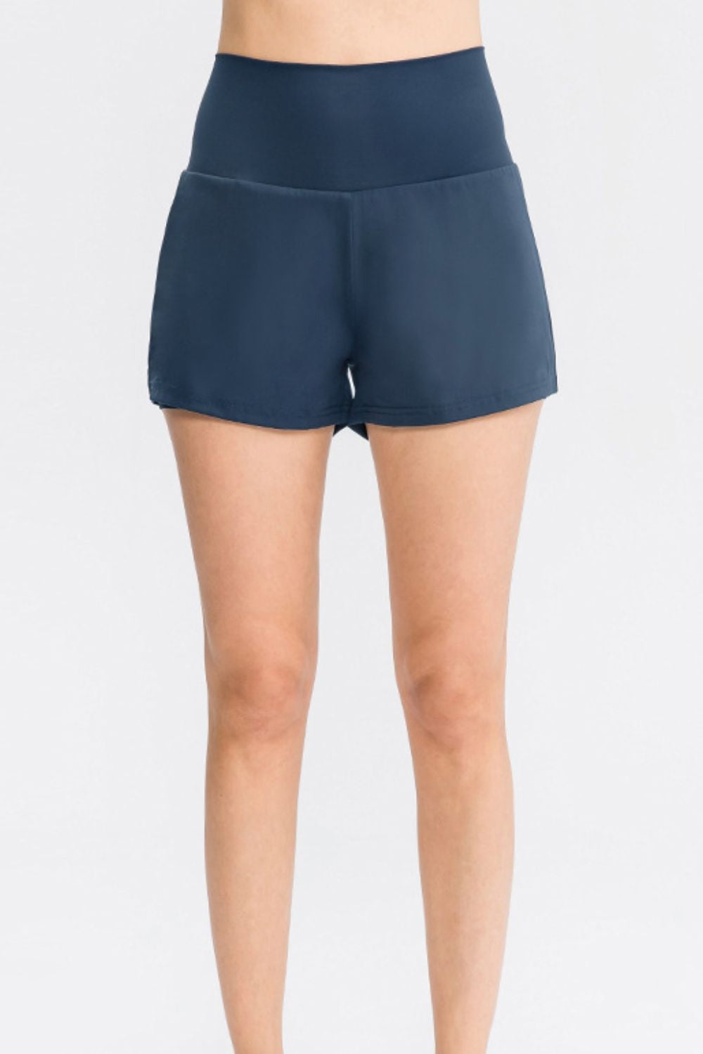 Model standing front-facing in solid navy sports shorts with a wide waistband, relaxed straight-leg silhouette, and neatly stitched hems.