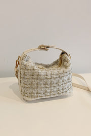 Small cream woven shoulder bag with a softly structured silhouette, short top handle, removable strap, zip-top closure, and sleek gold-tone hardware.