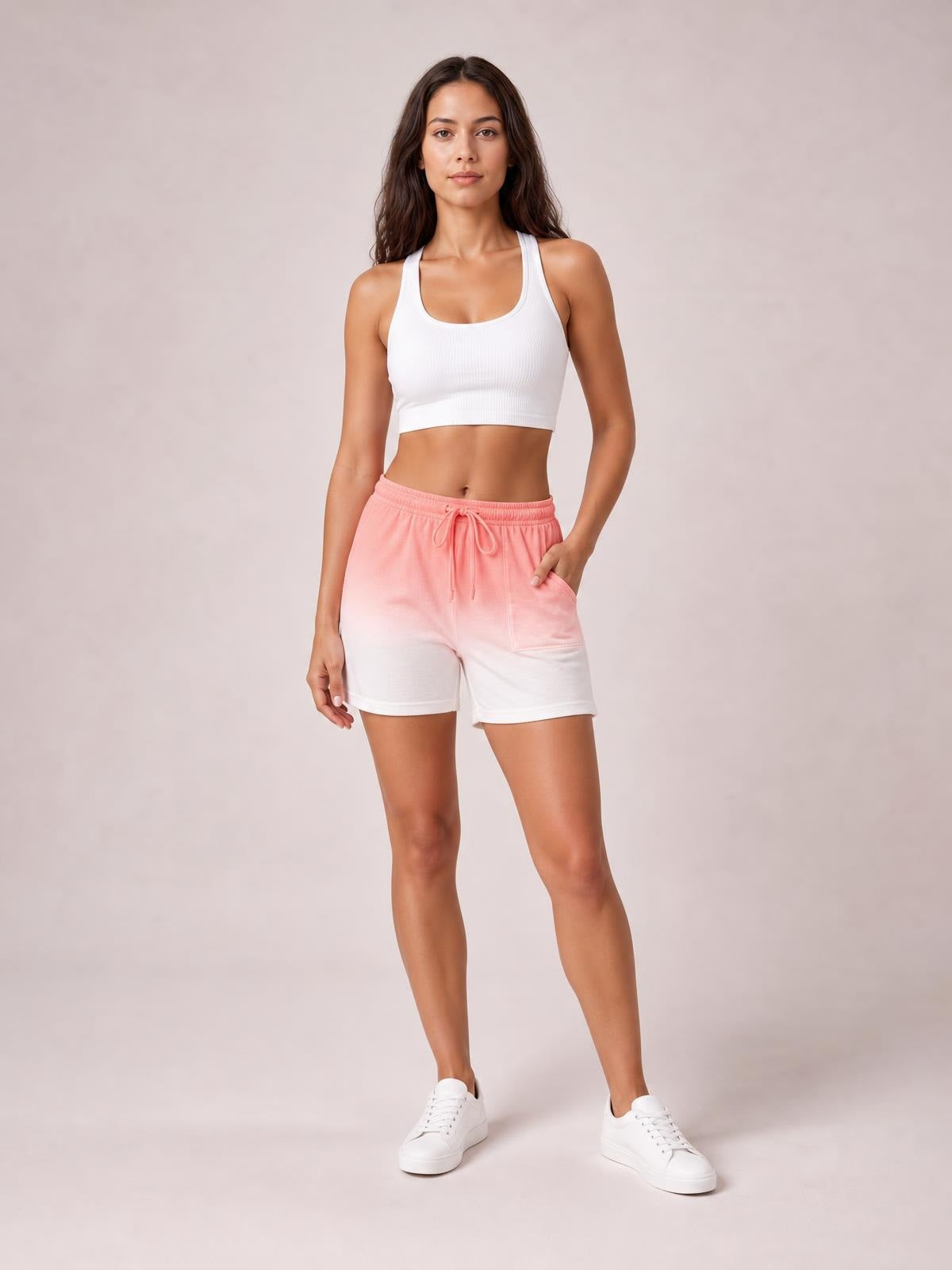 Model poses in coral dip-dye high-waisted shorts with a light-to-dark gradient, drawstring waistband, relaxed silhouette, and functional pockets.
