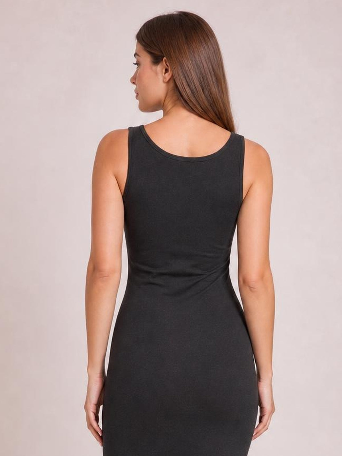 A model stands facing away in a black premium cotton sleeveless midi dress with a scoop neckline and fitted bodycon silhouette.