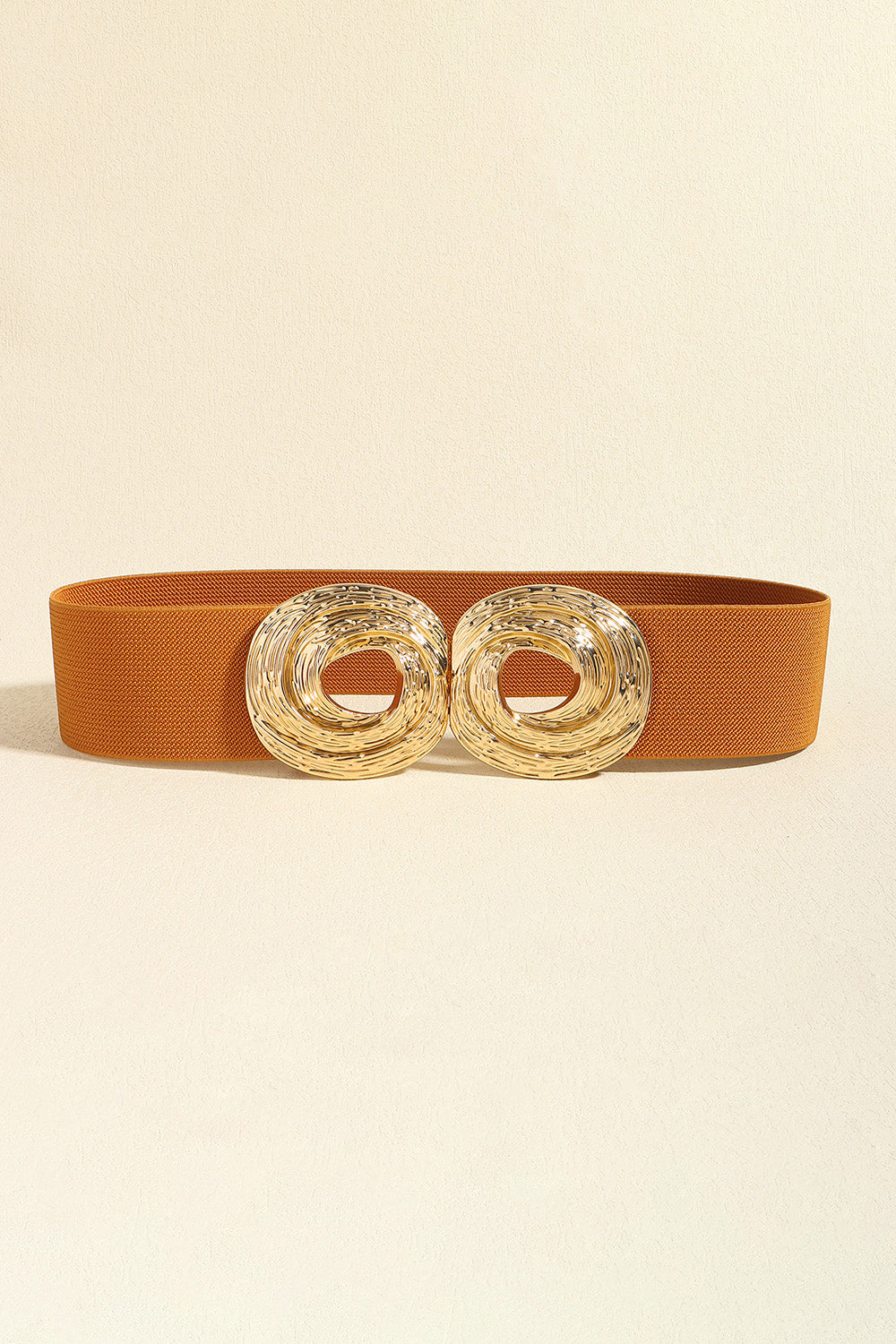 A rust-orange textured 2-inch belt features a polished zinc alloy buckle with two sculptural, intertwined circular rings.