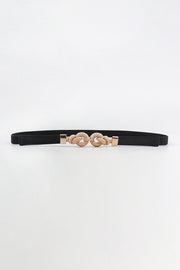 Slim black PU leather belt with a polished zinc alloy buckle featuring ornate interlocking rounded details and a sleek, streamlined silhouette.