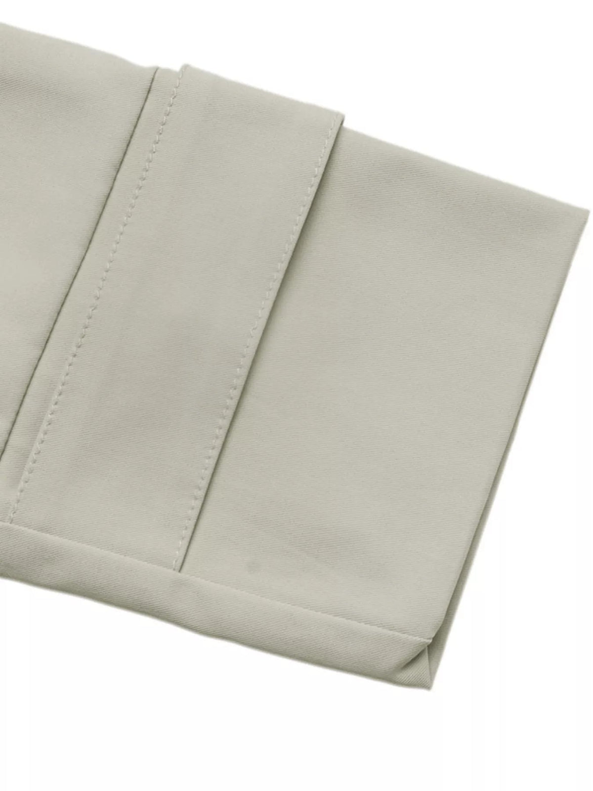 Close-up of a light gray cropped jacket showing smooth woven fabric, a neatly stitched panel seam, and a folded hem with clean construction.