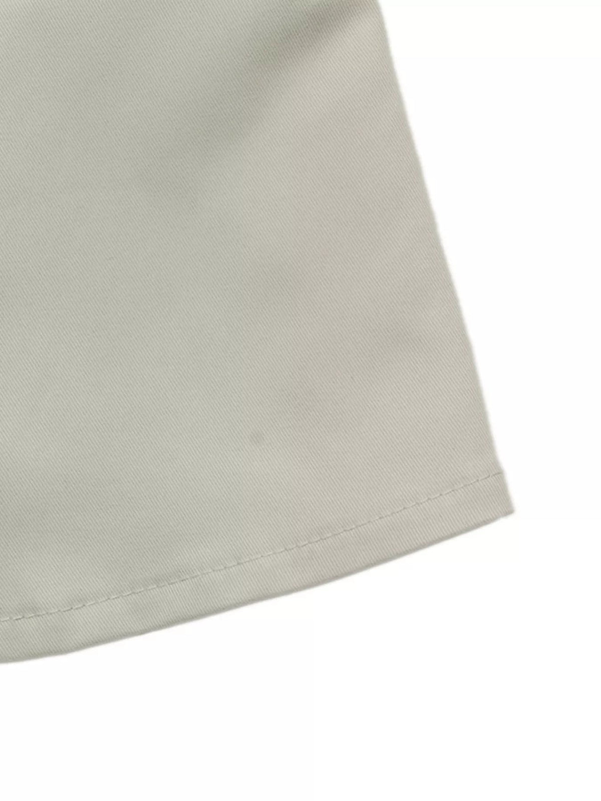 Close-up of the light gray cropped jacket fabric, showing its fine diagonal texture and neatly stitched double-layer hem construction.