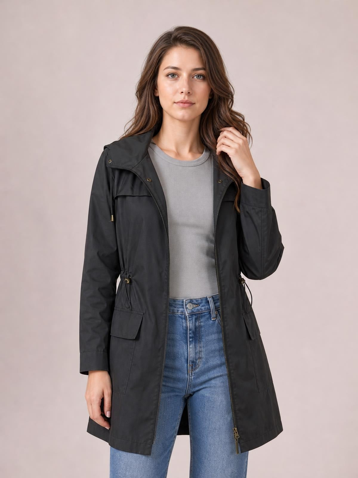 A model wears a black zip-up hooded jacket with a regular longline fit, drawstring waist, flap pockets, and an open front over a gray top.