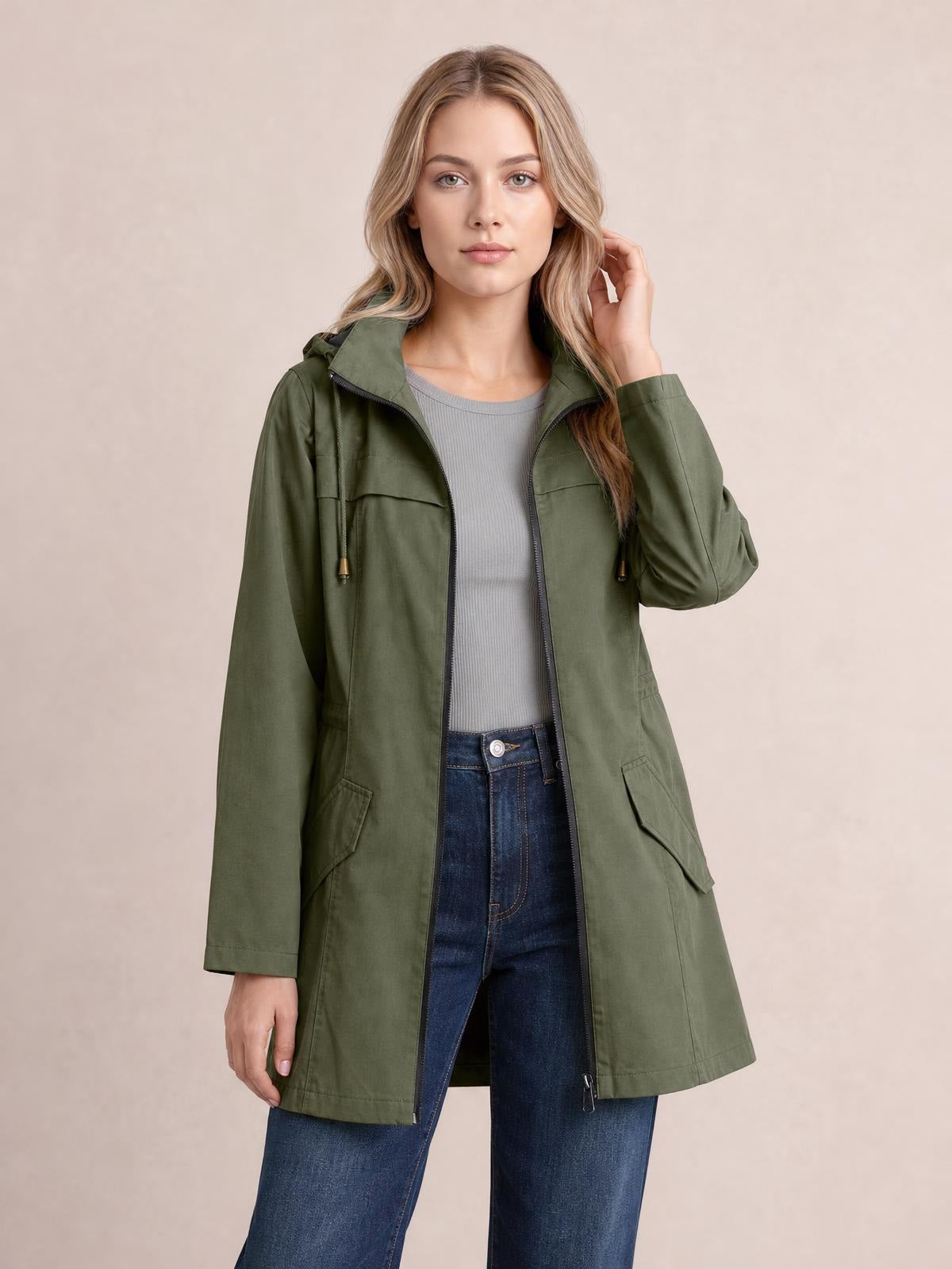 Model wears an olive green zip-up drawstring-waist hooded jacket with a long regular silhouette, flap pockets, and sleeves, touching her hair.