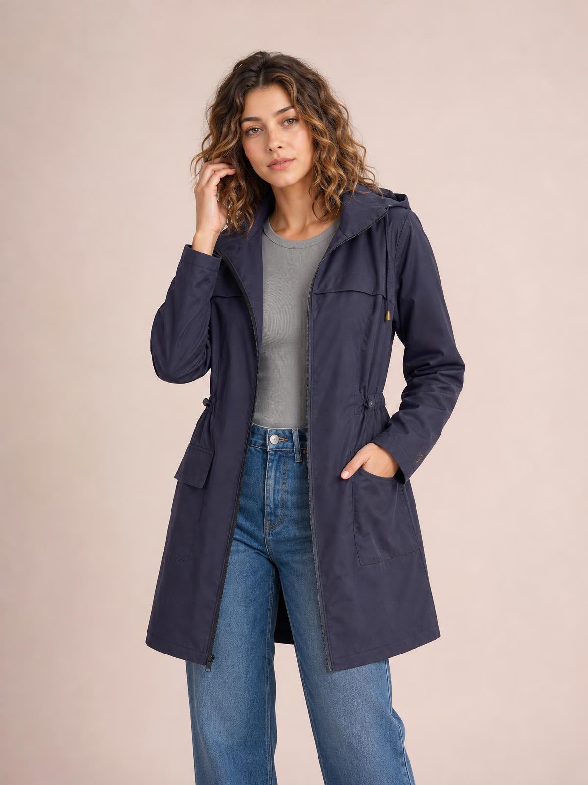 A model poses in a navy zip-up drawstring waist hooded jacket with a long regular silhouette, practical front pockets, and long sleeves.