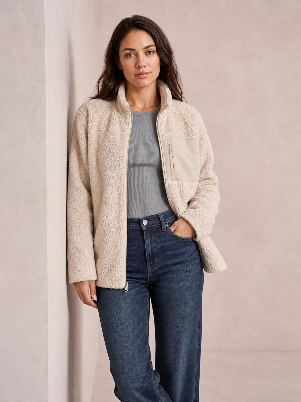 Model wears a cream plush jacket with long sleeves, a stand collar, full front zip, smooth chest pocket, and a relaxed straight silhouette.