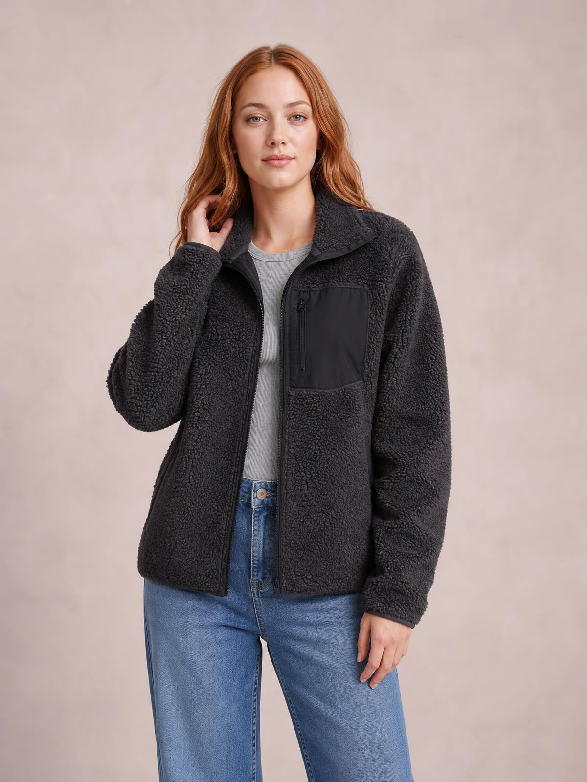 Model wears a black plush zip-up jacket with long sleeves, a soft stand collar, relaxed silhouette, front zipper, and a zippered chest pocket.