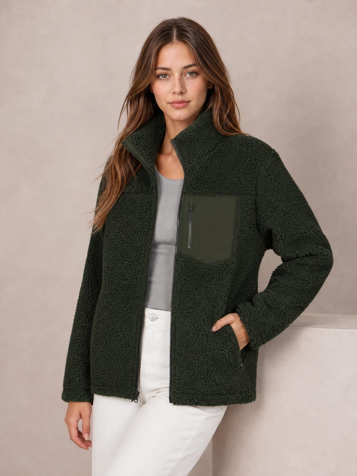 Model poses in a dark green plush jacket with a zip front, stand collar, long sleeves, chest pocket, and relaxed hip-length silhouette.