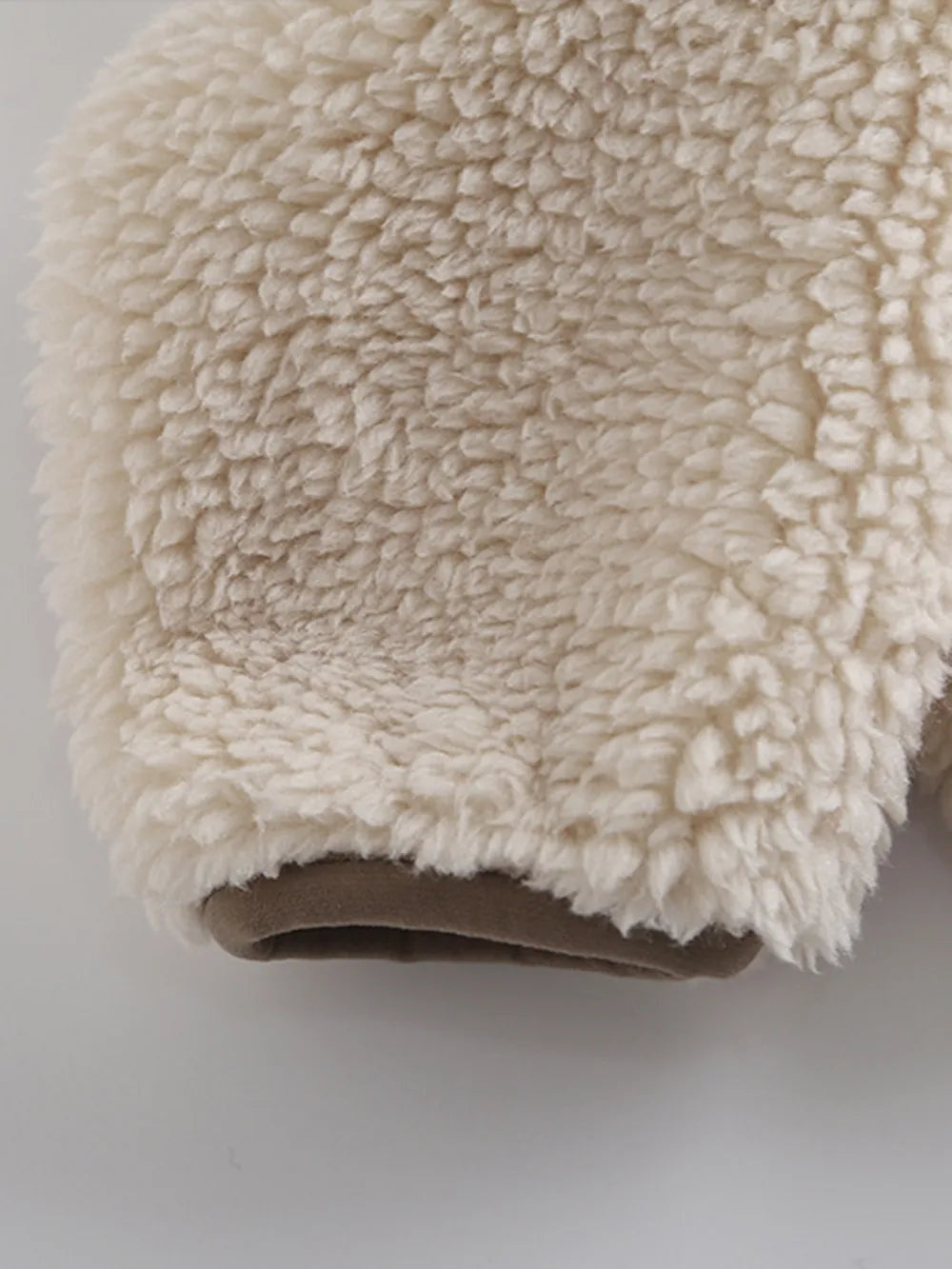 Close-up of a cream Zip Up Long Sleeve Plush Jacket sleeve, highlighting its thick curly sherpa texture and softly finished cuff opening.