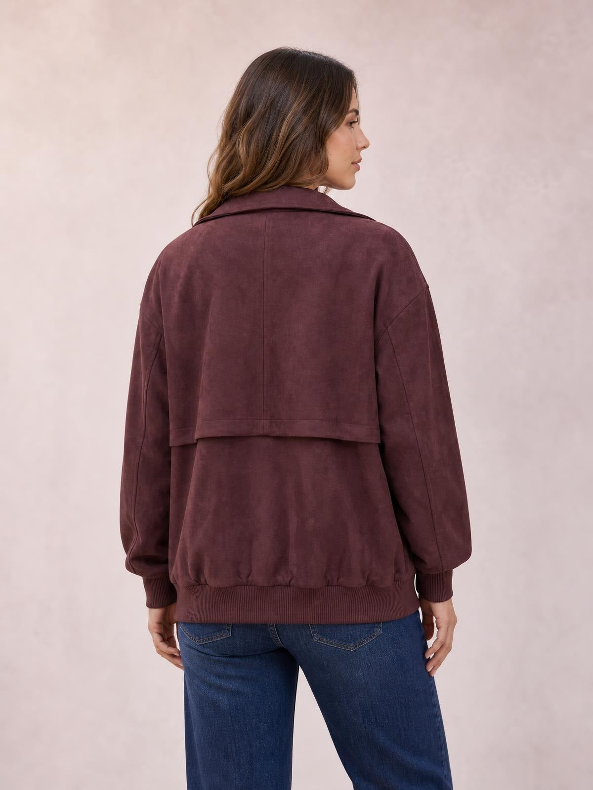 A model shown from behind wears a burgundy long-sleeve zip-up jacket with a wide collar, relaxed silhouette, seam detailing, and ribbed cuffs and hem.
